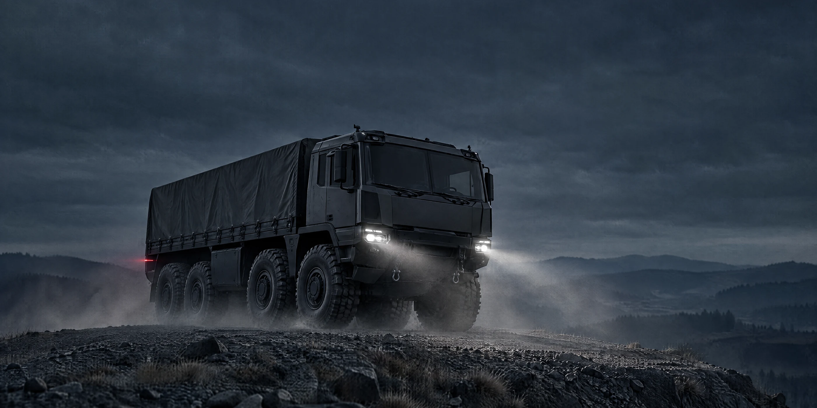 Tatra military truck on a rocky ridge at dusk with headlights on