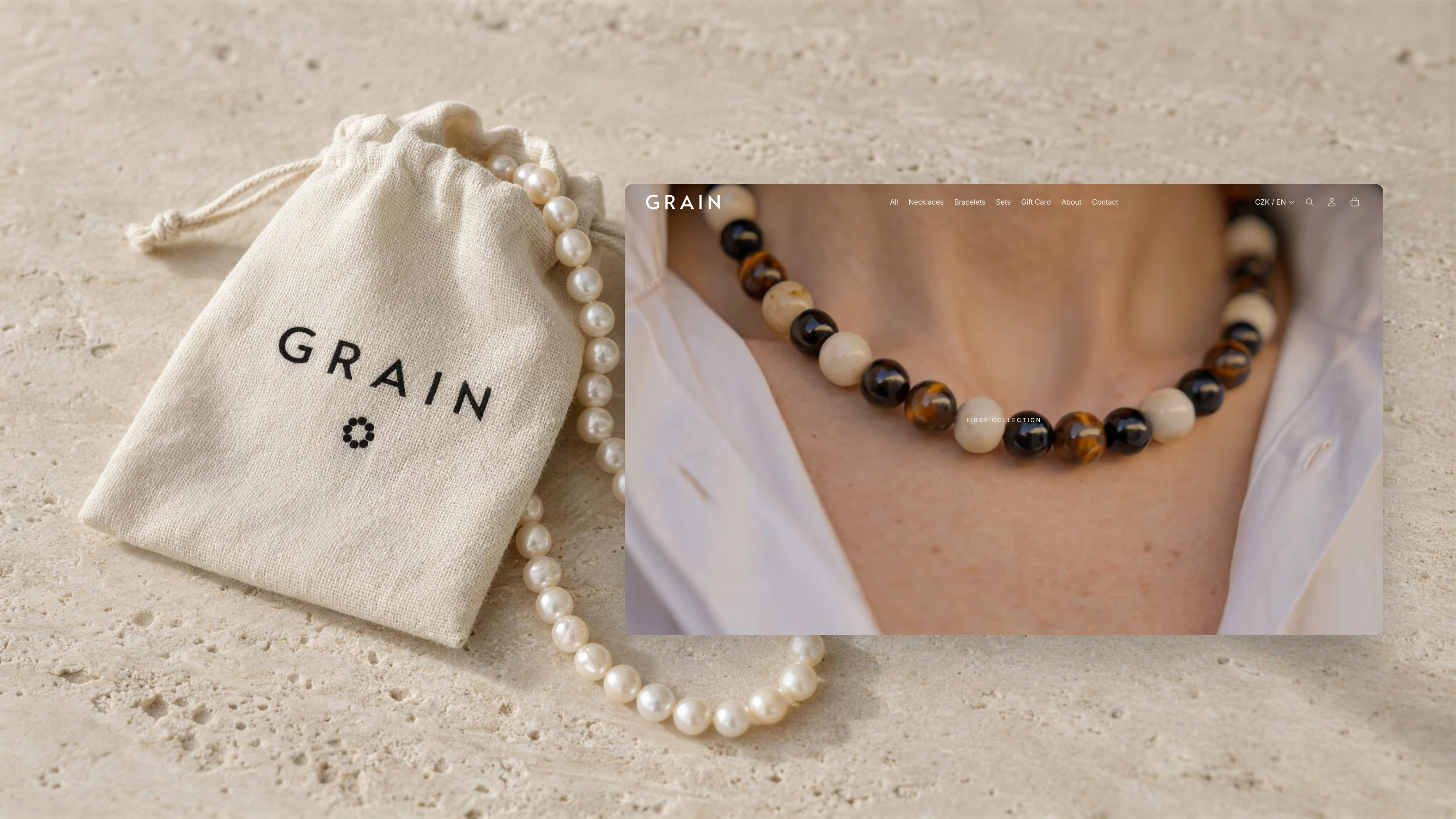 GRAIN homepage in a browser window over a linen pouch printed with the GRAIN logo and a strand of pearls on travertine