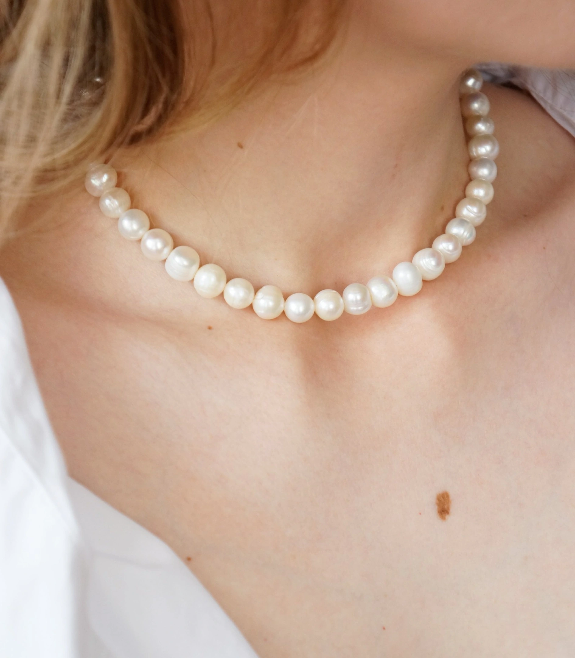 The Light necklace of freshwater pearls, worn with a white shirt
