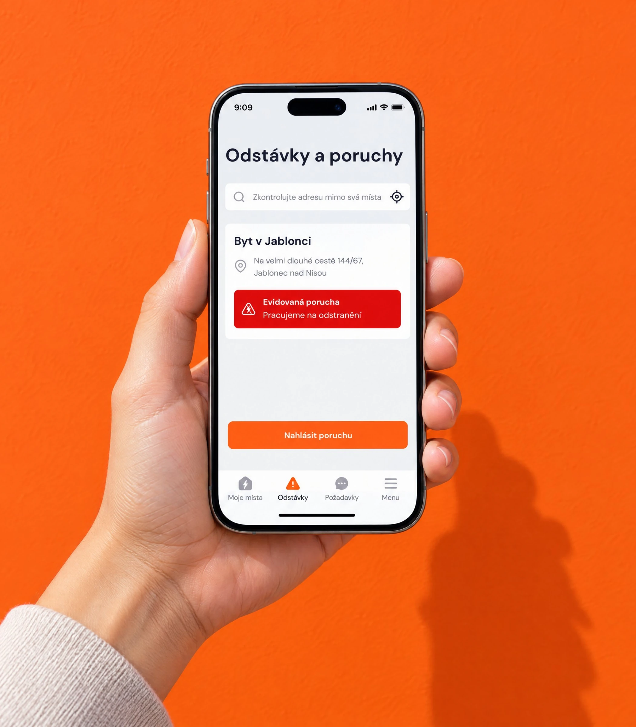 Hand holding a phone with the outages and faults screen against an orange wall
